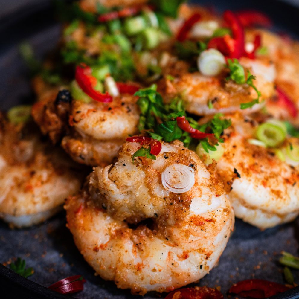 Eine Nahaufnahme einer Portion marinierter Garnelen mit Ananas Teriyaki Marinade und geschnittenen Lauchzwiebeln und Thai Basilikum getoppt.