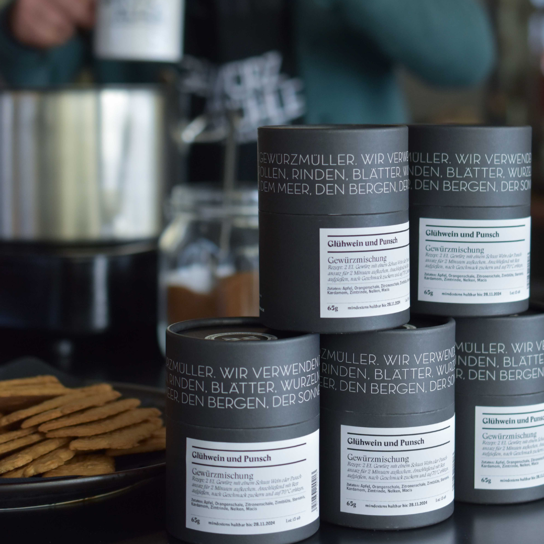 Gestapelte Glühwein und Punsch Gewürzmischungen in Dosen, im Hintergrund Spekulatius