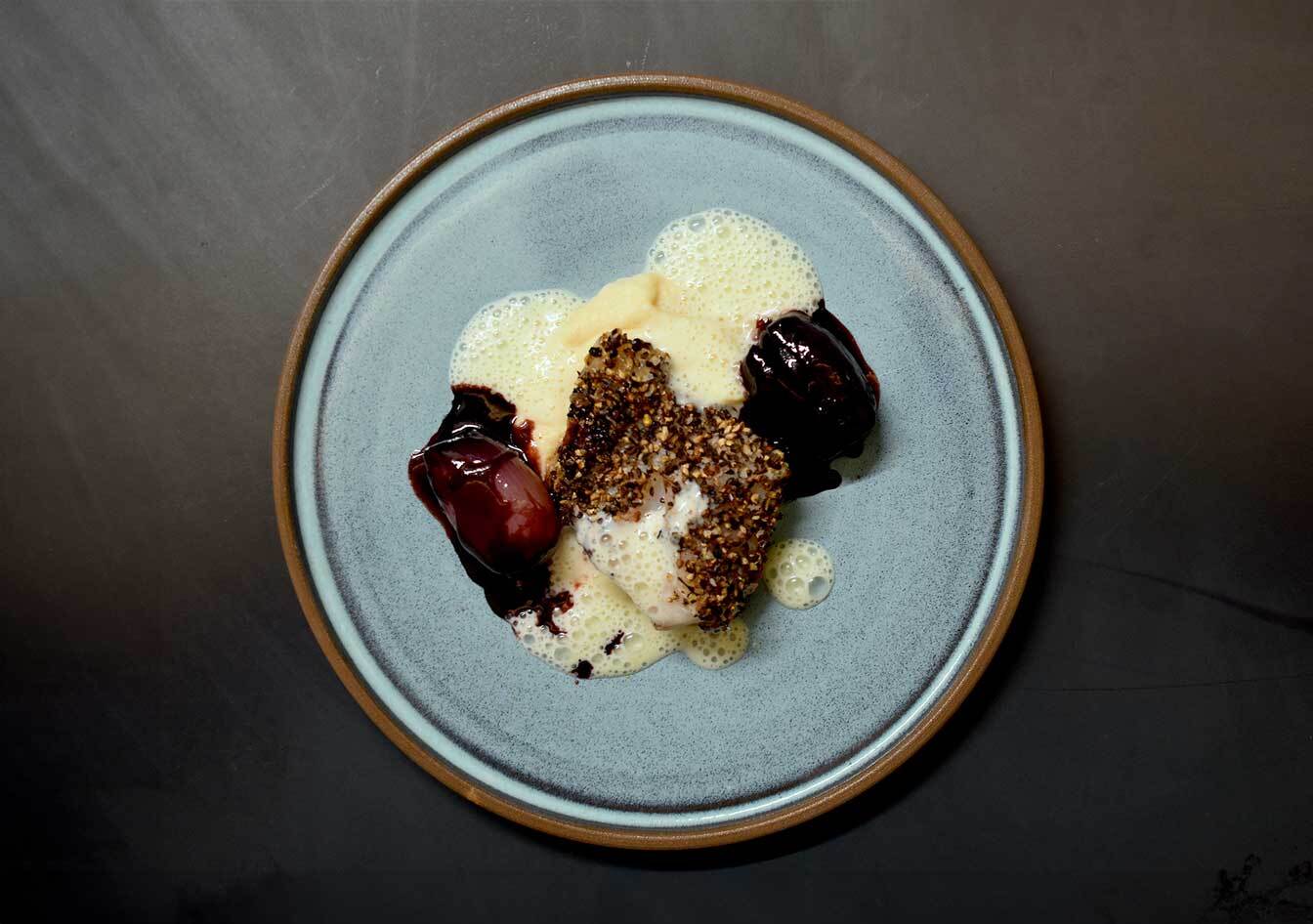 Rotbarschfilet mit knuspriger Gewürzkruste, cremigem Schaum und geschmorter roter Bete auf einem hellblauen Keramikteller – fein angerichtetes Fischgericht mit intensiven Aromen, ideal für moderne Genussküche.