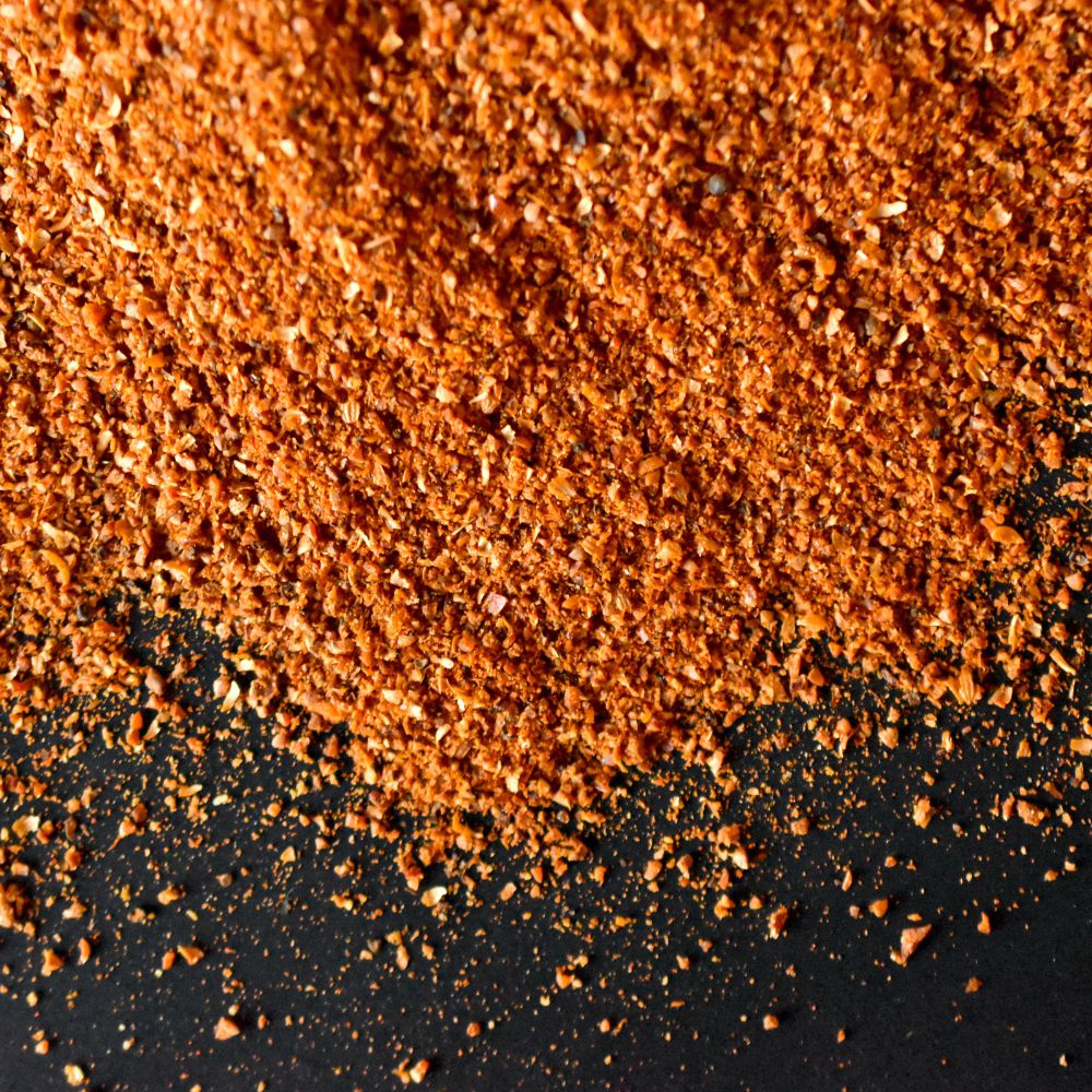 Harissa Gewürz auf schwarzem Untergrund verstreut 