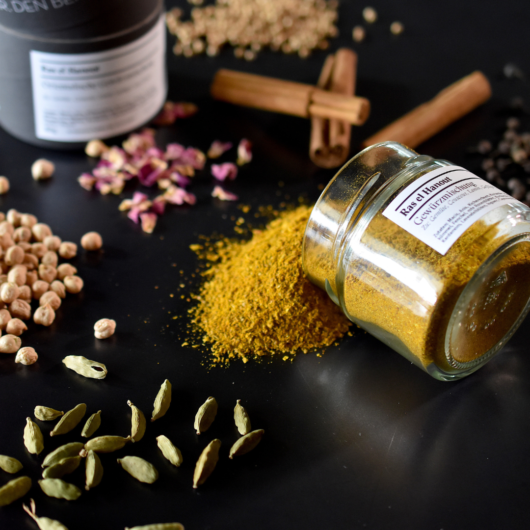 Ras el Hanout Glas ausgeschüttet auf einem Tisch mit mehreren Zutaten