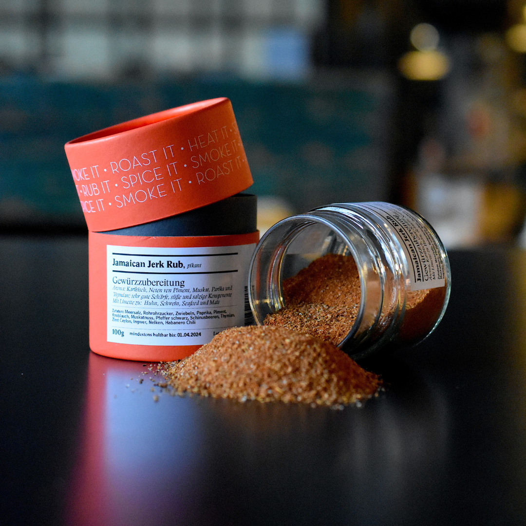 Jamaican Jerk Rub Gewürzzubereitung - Gewürzdose und umgekipptes Glas auf schwarzem Tisch