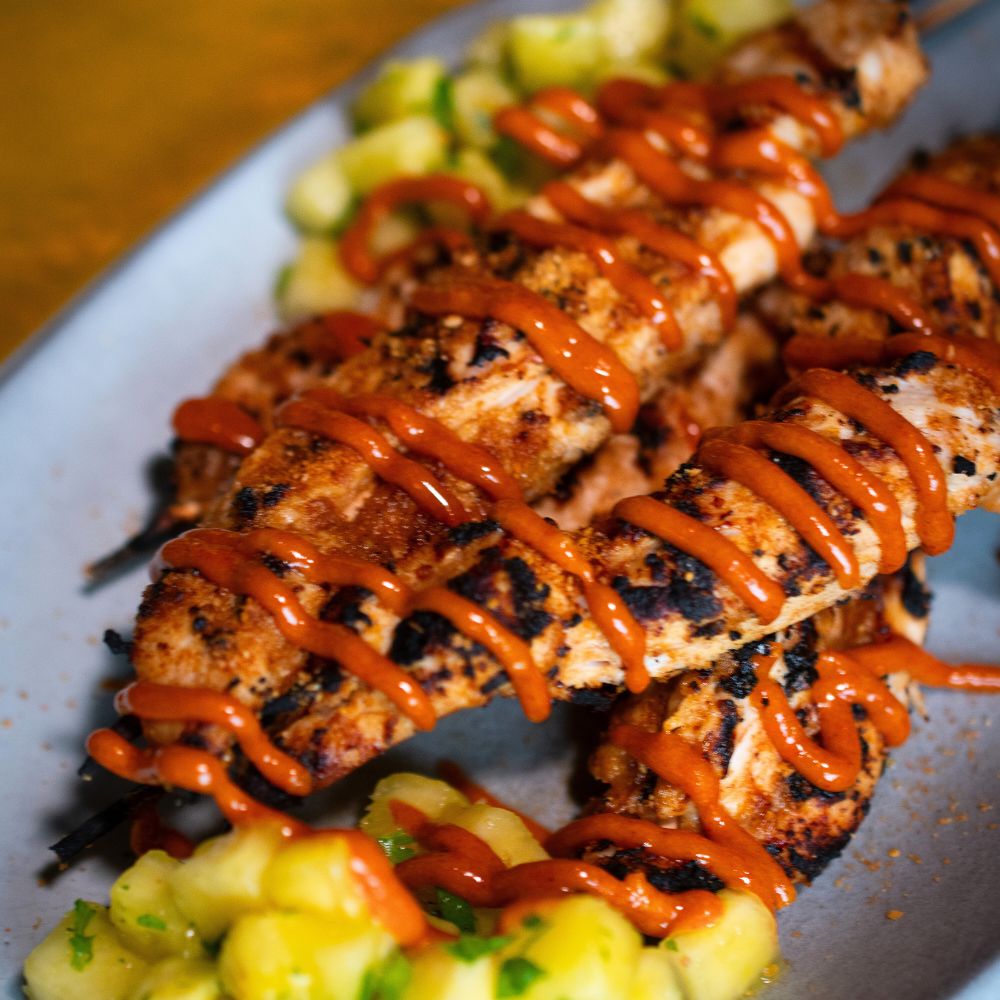 Drei Hähnchenspieße mit Ananas Teriyaki Rub mariniert und einer Salsa garniert liegen auf einer Platte mit selbst gemachter Salsa