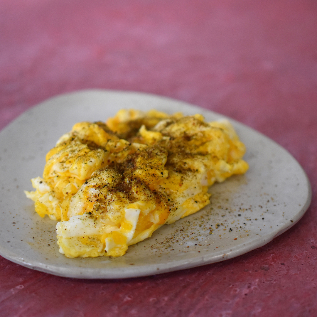 Rührei auf einem Teller serviert, gewürzt mit Zitronensalz